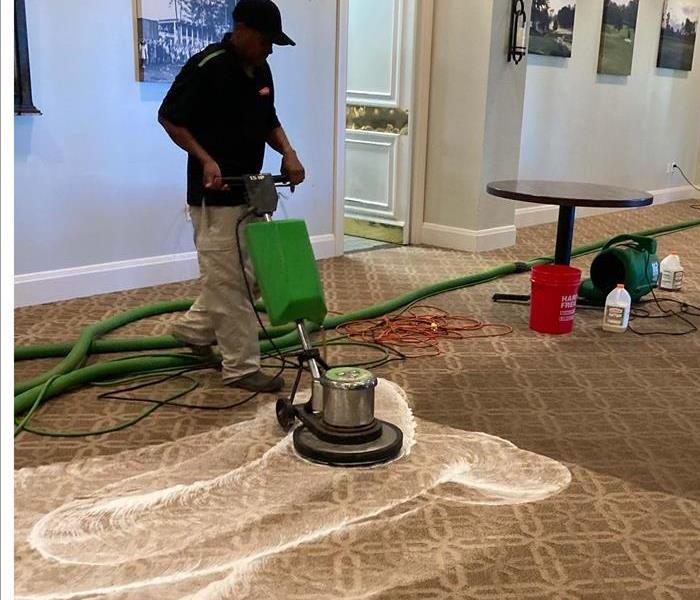 Photo of male employee cleaning carpet